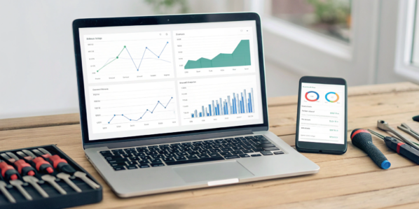 Using inventory and order management software on a laptop and phone at a desk with tools.
